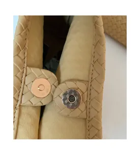 Detailed view of the woven leather shoulder bag featuring a secure magnetic snap closure hardware.