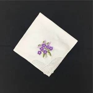 Detailaufnahme eines weißen Baumwolltaschentuchs mit lila Blumenstickerei und Spitzenrand.