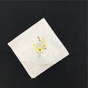 Detailansicht eines weißen Baumwolltaschentuchs mit feiner Spitzenborte und Blumenstickerei.