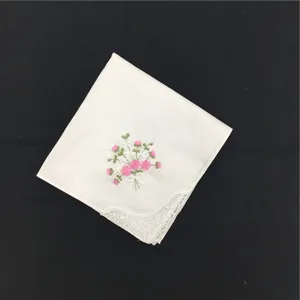 Detailansicht eines weißen Baumwolltaschentuchs mit zarter rosa Blumenstickerei und Spitzenecke.