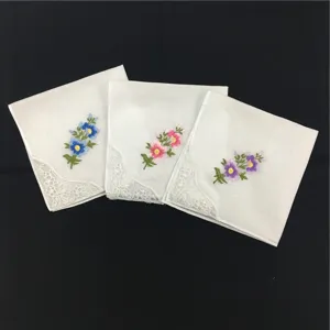 Details weißer Baumwolltaschentücher mit zarter Blumenbestickung und eleganter Spitzenkante.