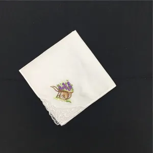 Detailaufnahme eines weißen Baumwolltaschentuchs mit feiner Spitzenborte und Blumenstickerei.