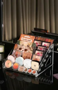 Transparent acrylic tiered cosmetic organizer for eyeshadow palettes and makeup display shelves.