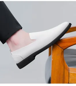 Close-up detail of white slip-on men's leather shoe with black sole resting on a wooden chair.