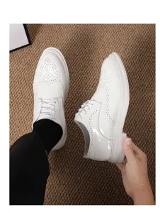 Vista dettagliata delle scarpe stringate bianche da uomo in stile brogue con decorazioni.