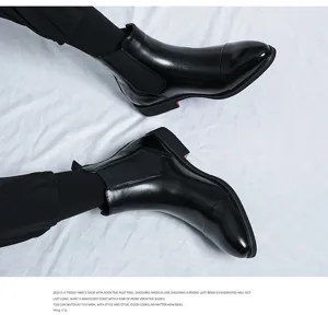 Close-up of men's black leather pointed toe Chelsea boots showcasing premium glossy finish.