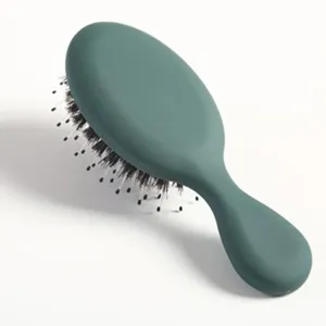 Vue détaillée de la brosse à cheveux ovale vert foncé, outil de massage à poils doux pour soins.