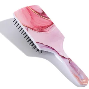 Vue détaillée de la brosse à cheveux rose effet marbre avec une poignée ergonomique.