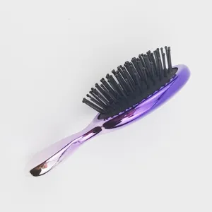 Vue détaillée de la brosse à cheveux galvanisée violette avec poils coussinés noirs, outil.