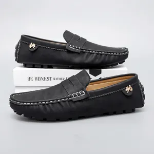 Detailed view of black leather loafers showing contrast white stitching and side metallic ornament.