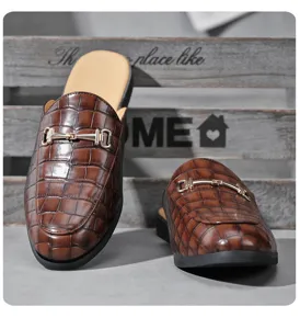 Detailed view of men's crocodile embossed leather slip-on mule with gold metal horsebit.