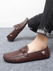 Close-up detail of brown leather mens loafers featuring metal buckle and contrast stitching