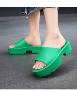 Close-up detail shot of green platform slide sandals featuring a chunky thick sole and open toe.
