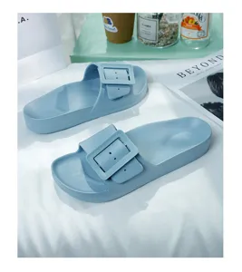 Blue minimalist slip-on sandals with decorative buckle detail in detail shot view.