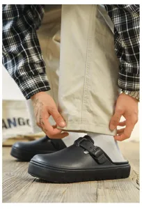 Detail shot of black winter fleece-lined clogs with adjustable buckle strap, casual warm shoes.