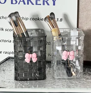 Transparent woven makeup brush holder detail shot, clear plastic pen organizer with pink bow.