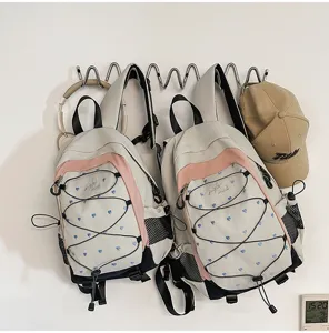 Detail shot of sweet heart pattern school backpack with elastic cords and side mesh pockets.