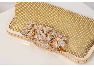 Gold rhinestone evening clutch bag detail showing sparkling crystals and metallic leaf clasp.