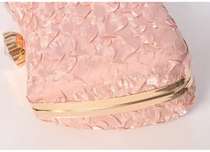 Exquisite pink evening clutch bag detail view, featuring textured floral fabric and gold frame.
