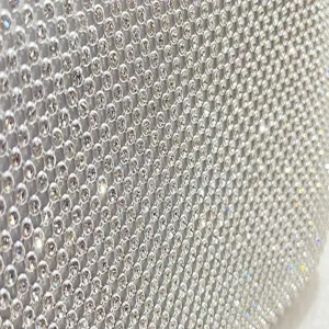 Close-up detail of glittering rhinestone mesh surface, sparkling crystal evening bag texture.