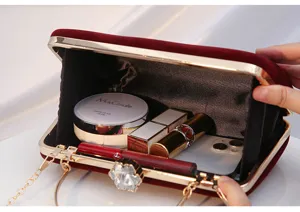 Red velvet evening clutch bag with metal frame and chain strap, elegant party handbag.
