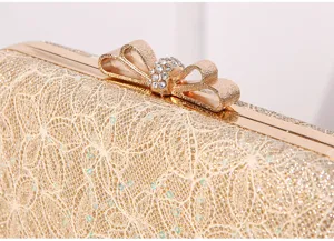 Close-up view of gold evening clutch bag with lace glitter and rhinestone bow clasp.