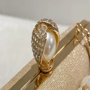 Close-up detail of luxury evening clutch, rhinestone pearl clasp, exquisite metallic texture.