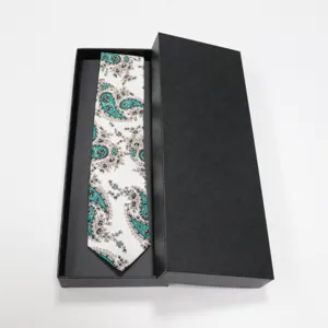 Vue détaillée d'une cravate cachemire élégante dans sa boîte cadeau noire, motif blanc et bleu.