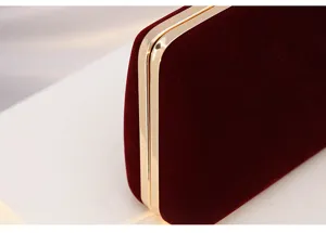 Burgundy velvet evening clutch bag detail showing soft texture and luxury gold metal frame.