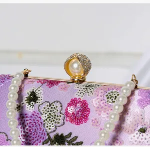 Nahaufnahme einer lila Pailletten-Abendtasche, feine Blumenstickerei mit Perlenhenkel.