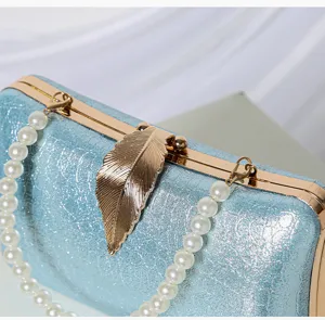 Exquisite detail shot of light blue glitter evening clutch featuring gold leaf clasp and pearl handle.