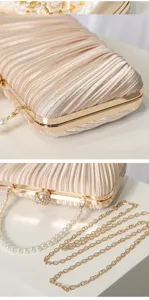 Detailed view of the champagne pleated evening clutch with pearl handle and metal chain strap.