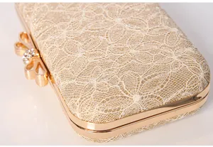 Exquisite lace evening clutch bag detail showing gold metal frame and rhinestone bow.