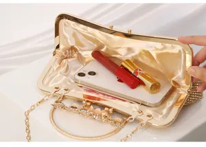 Detailed view of gold evening clutch bag interior showcasing capacity for phone and cosmetics.
