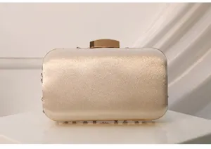 Detailed view of luxury champagne satin evening clutch with metallic gold clasp and rhinestones.
