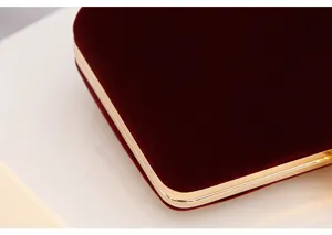 Close-up detail of luxury red velvet evening clutch bag with golden metal frame edges.