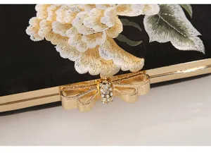 Detail view of black satin evening clutch bag with exquisite floral embroidery and bow clasp.