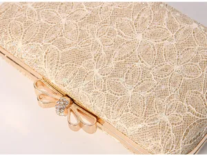 Gold lace evening clutch bag detail showing exquisite floral texture and rhinestone bow clasp.