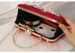 Elegante bolso de noche de terciopelo con decoración de perlas y marco de metal dorado.