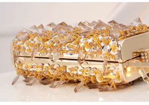 Close-up detail of luxurious gold beaded evening clutch bag with sparkling crystals and sequins.