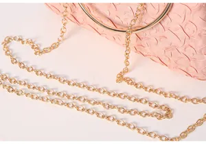 Close-up detail of elegant pink evening clutch featuring luxury gold chain strap and ring.