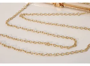 Detailed view of luxury gold chain strap and crystal clasp on an elegant evening clutch bag.