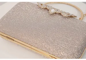 Primer plano de bolso de noche con purpurina dorada y elegante cierre de pedrería brillante.