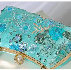 Detailed close-up of teal beaded sequin evening bag with floral embroidery and pearl clasp.