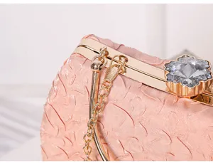 Detailed view of pink evening clutch bag metal frame crystal flower clasp luxury accessory.