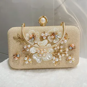Elegant gold glitter evening clutch bag with pearl floral and rhinestones for women banquet.