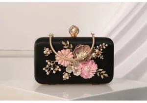 Elegante bolso de noche de satén negro con aplicaciones florales hechas a mano y cierre dorado.