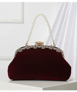 Close-up of velvet evening bag featuring pearl handle and rhinestone clasp details.