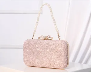 Close-up detail of elegant pink lace evening clutch featuring luxury pearl handle and bow clasp.