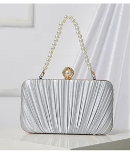 Close-up detail of silver pleated evening clutch bag with elegant pearl handle and embellished clasp.